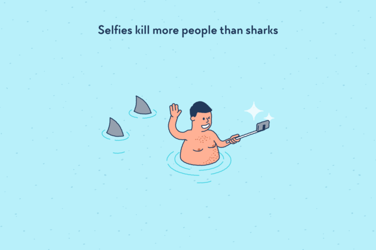 Man making a selfie in the sea, two sharks swimming behind him.